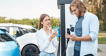 couple looking at phone to find charging station for electric vehicle